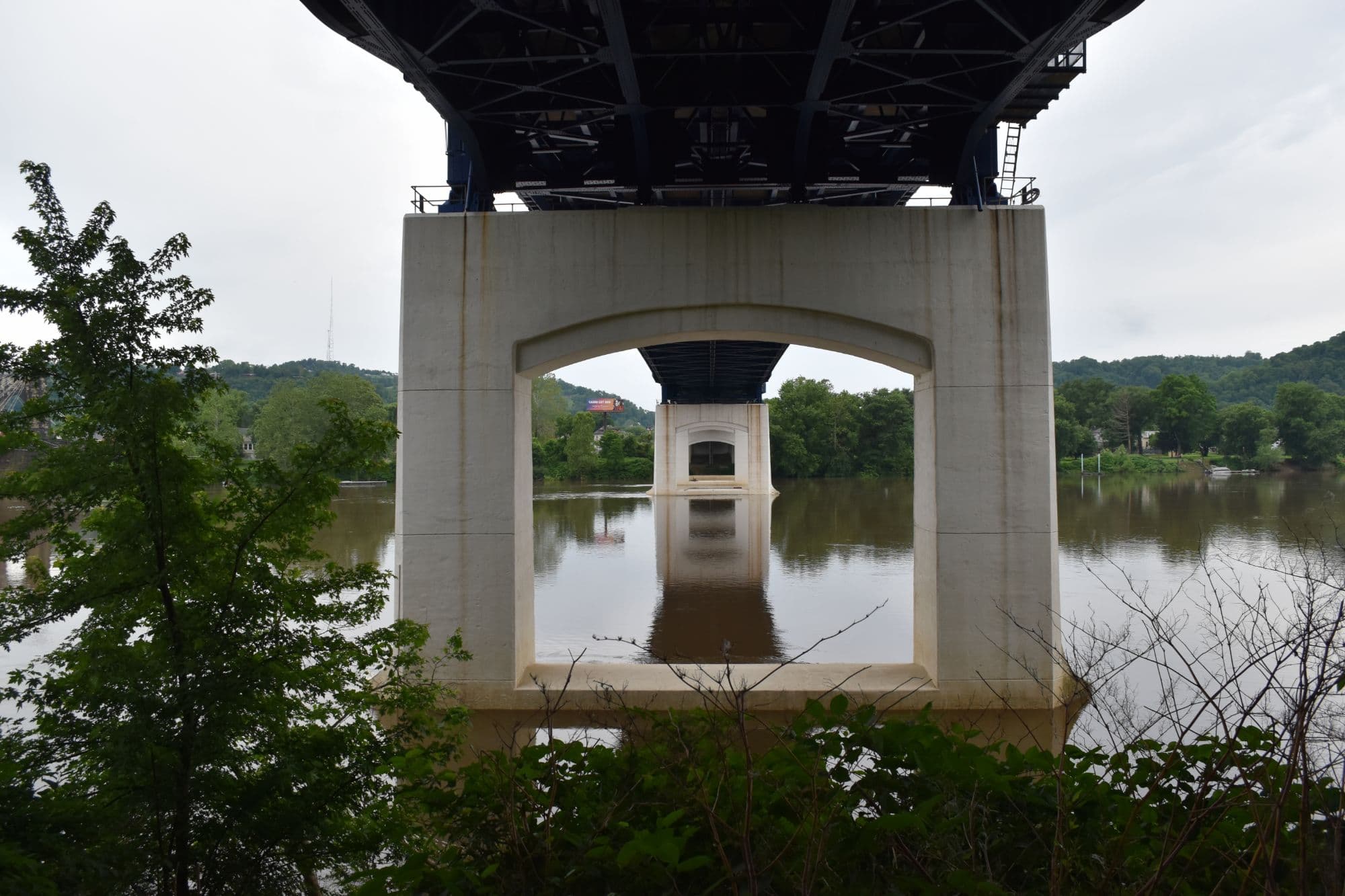 Looking up through the concrete arches under a bridge.