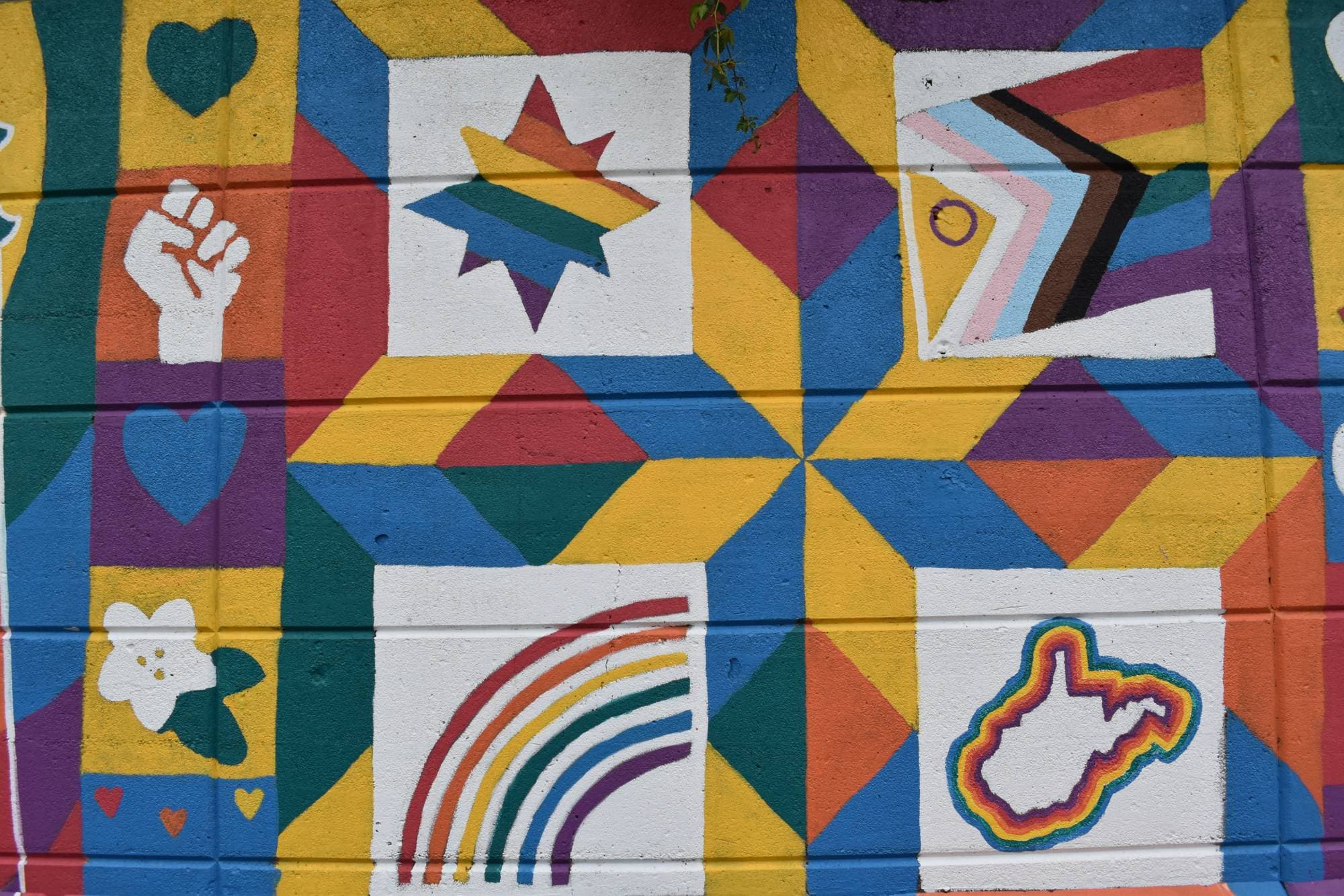 A colorful geometric mural with hearts, a rainbow, and a rainbow-outlined West Virginia.