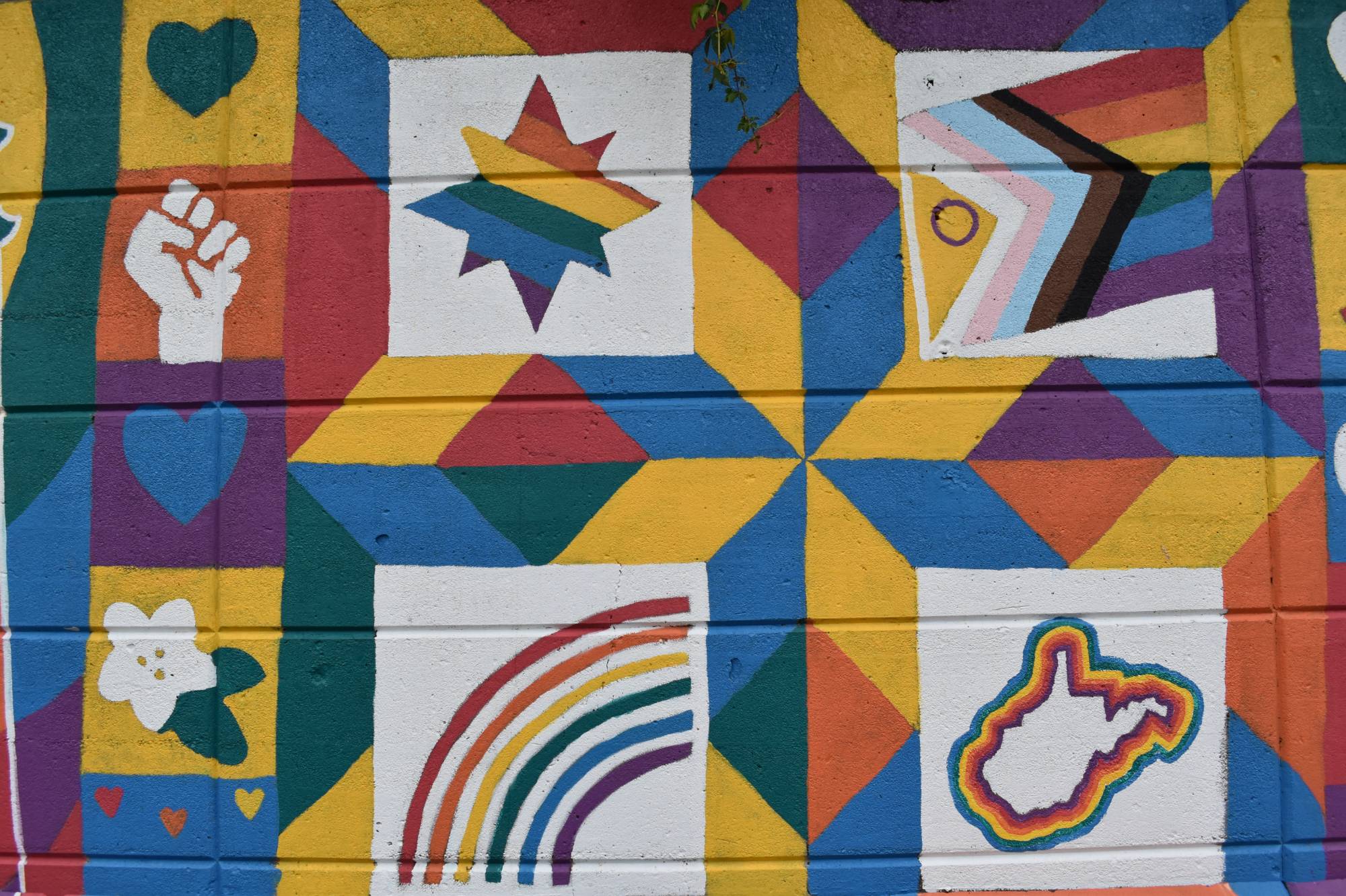 A colorful geometric mural with hearts, a rainbow, and a rainbow-outlined West Virginia.